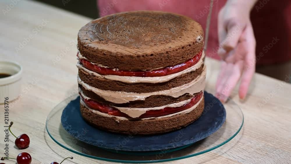 Step-by-step preparation of black designer cake. The confectioner covers the cake with cream. Step-by-step preparation of black designer cake. The confectioner covers the cake with cream.