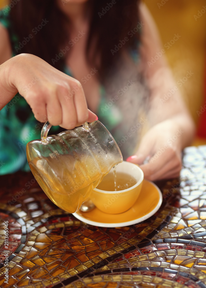 woman pours green tea into the cup woman pours green tea into the cup