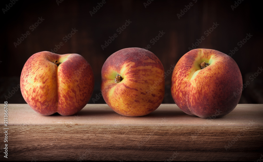 Peaches fresh colorful close up arrangement on wooden table and dark background in studio Peaches fresh colorful close up arrangement on wooden table and dark background in studio