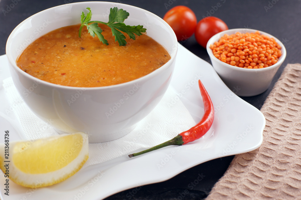 Lentil soup in a plate, next to vegetables and a slice of lemon Lentil soup in a plate, next to vegetables and a slice of lemon