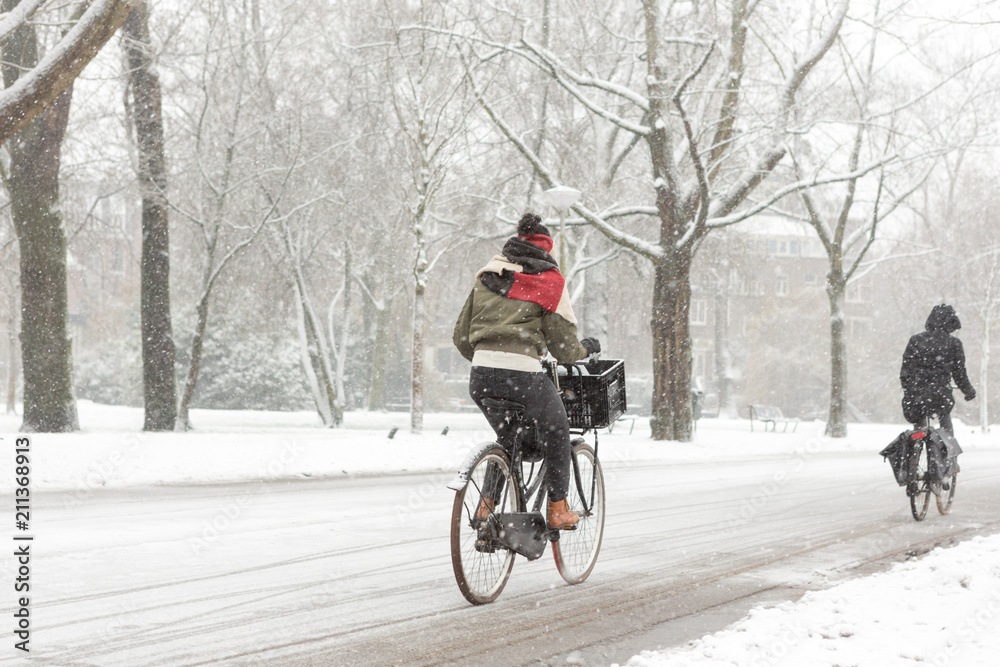 Woman biking in a snowy Amsterdam Vondelpark.