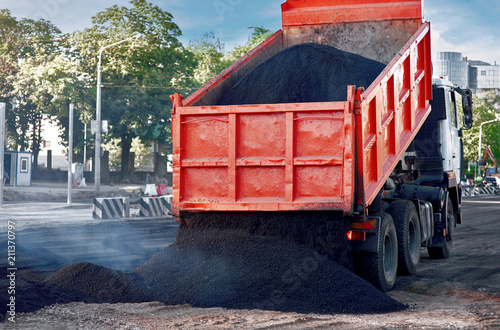 Canvas Print Heavy tipper unloads fresh hot smoking asphalt mix on a prepared surface for paving