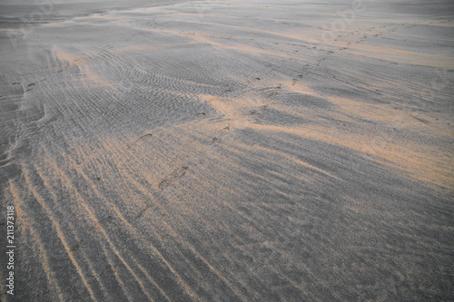 Alone human footprints on dunes of gray sand beach 