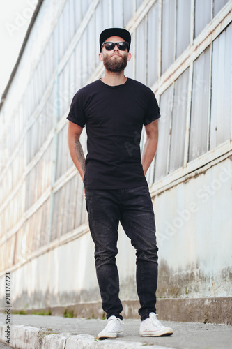 Hipster handsome male model with beard wearing black blank t-shirt with space for your logo or design in casual urban style © 4Max