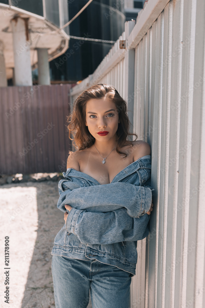 Beautiful girl in stylish and fashionable clothes with makeup on a summer sunny day. Smiling and serious Beautiful girl in stylish and fashionable clothes with makeup on a summer sunny day. Smiling and serious