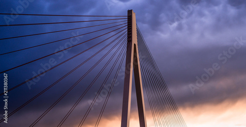 High suspended road bridge in Germany against a dark stormy sky at sunset.