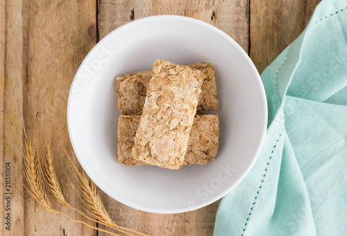 Wheat biscuit cereal in bowl on rustic wooden table, top view photo