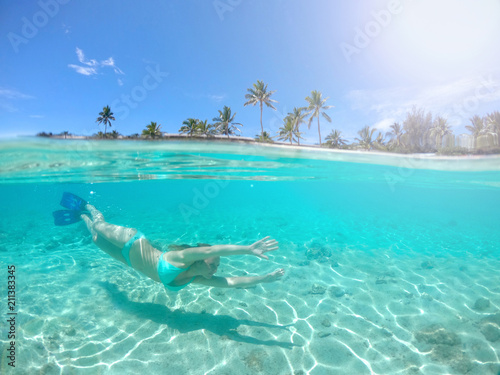 HALF-HALF: Young female traveler diving in the tranquil crystal clear water.