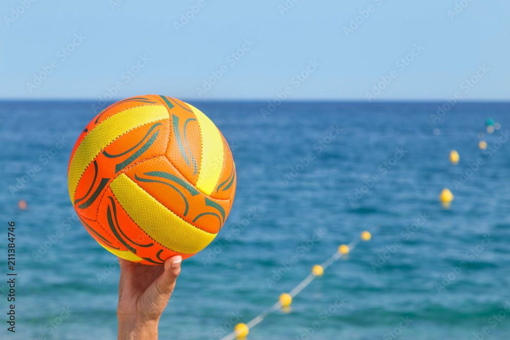 ball in the hands of a girl with a beautiful manicure on the background of the sea