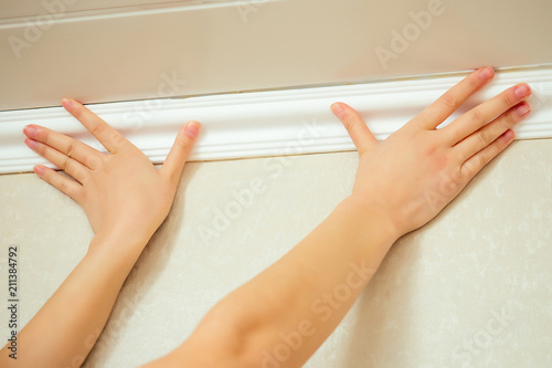 humans hands put a ceiling skirting on the ceiling