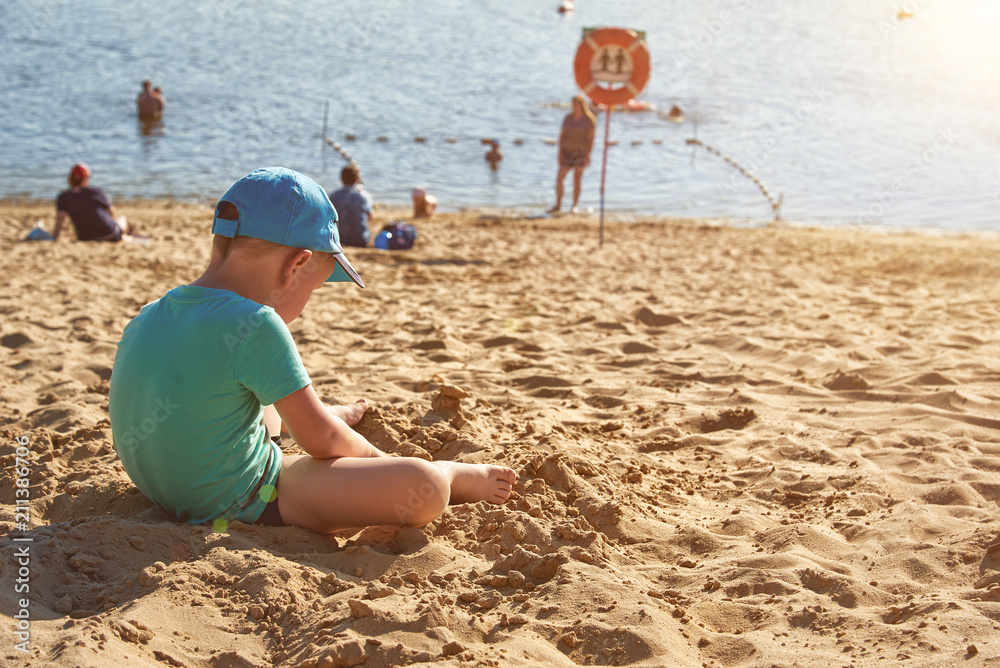 The child indulges on the beach in the cap with a smiley face. The child indulges on the beach in the cap with a smiley face.