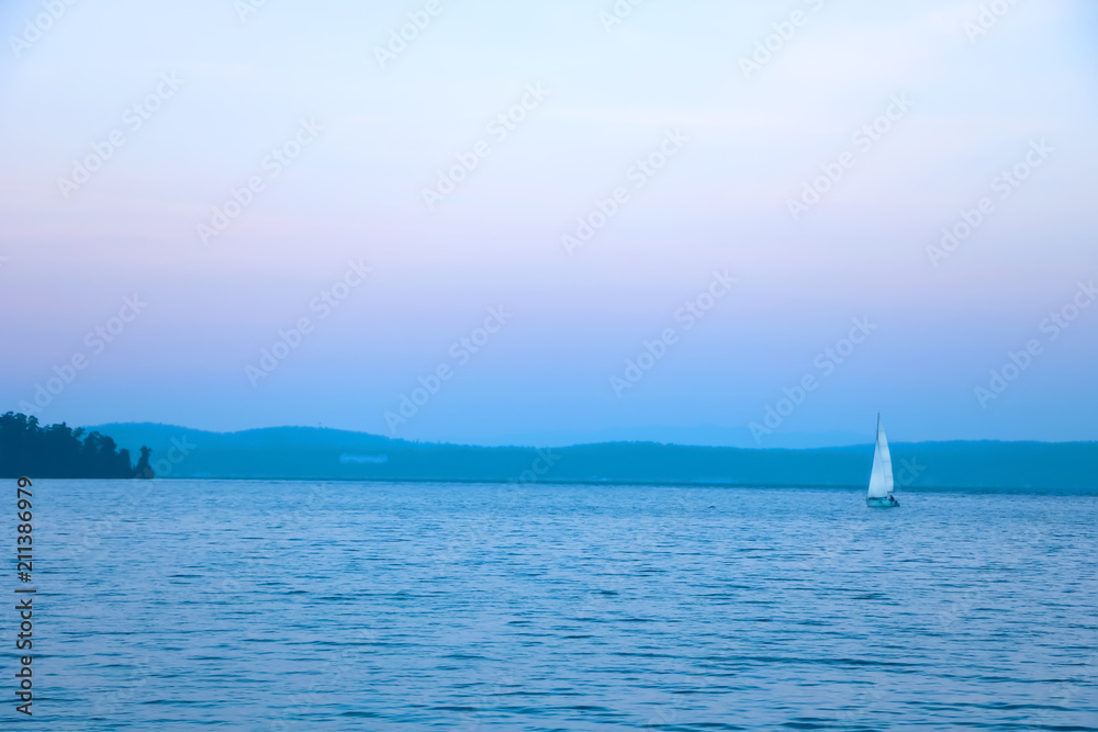 landscape on a big lake with a yacht and blue sky