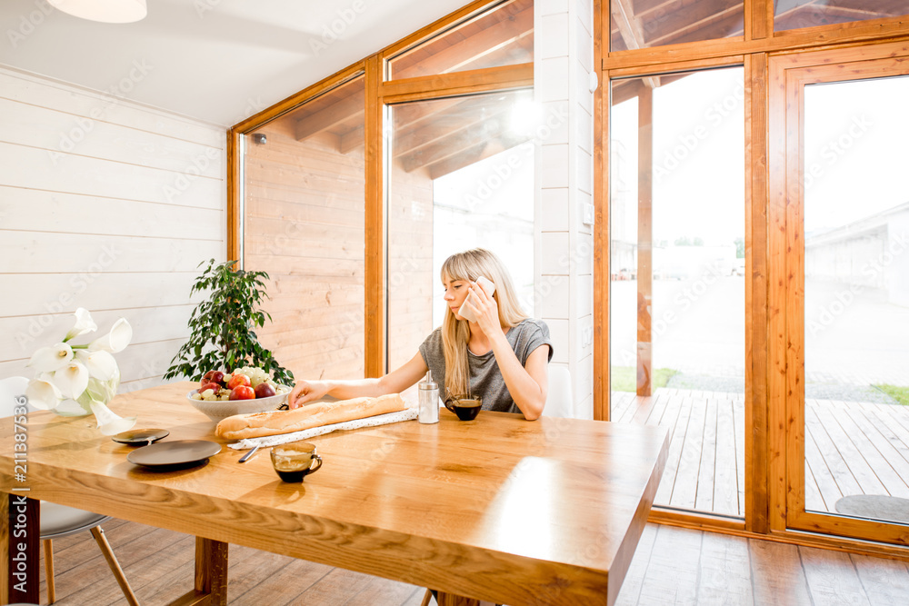 Woman talking with phone during a breakfast in the modern country house Woman talking with phone during a breakfast in the modern country house
