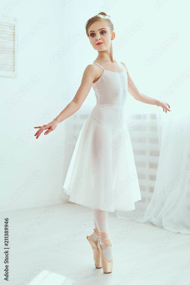 Beautiful ballerina is posing and dancing in a white studio full of light. The photo greatly reflects the incomparable beauty of a classical ballet art. Beautiful ballerina is posing and dancing in a white studio full of light. The photo greatly reflects the incomparable beauty of a classical ballet art.