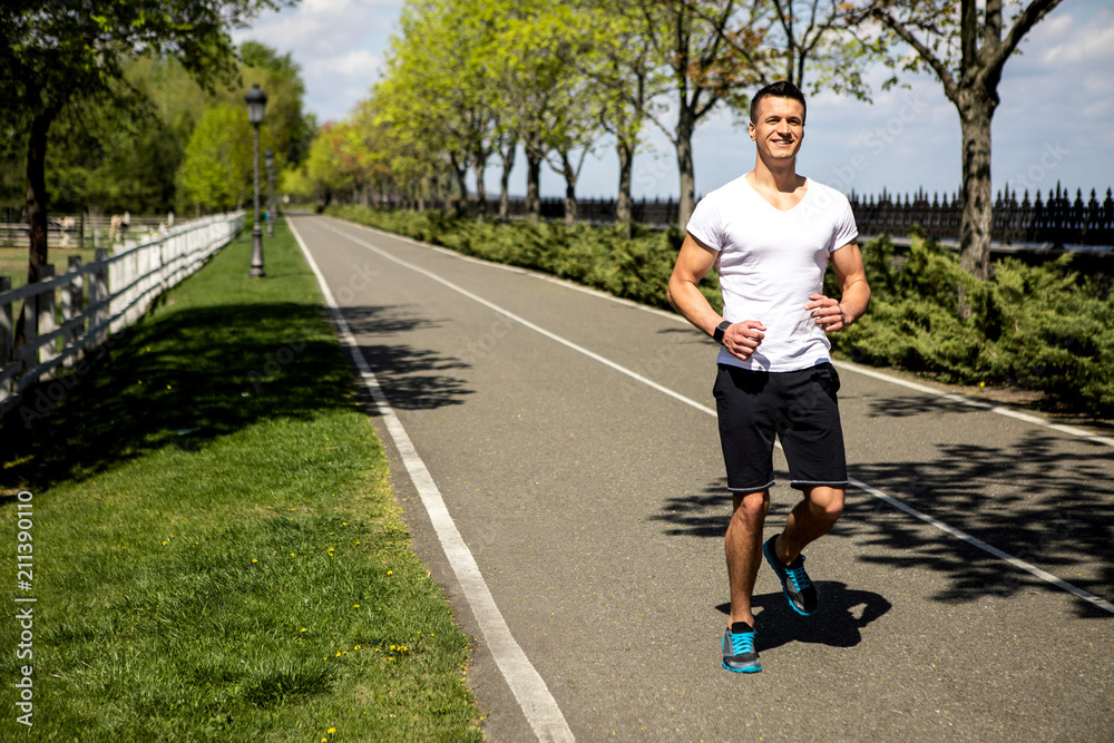 Grinning guy is enjoying running through scenic landscapes. He is wearing smartwatch while spending day actively outside. Copy space in left side Grinning guy is enjoying running through scenic landscapes. He is wearing smartwatch while spending day actively outside. Copy space in left side