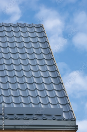 Grey Steel Tile Roof Texture Background, Gray Tiled Roofing. Large Detailed Vertical Closeup, Modern Residential House Rooftop Tiles Detail Textured Pattern. Bright Sunny Sky Summer Cloudscape Clouds
