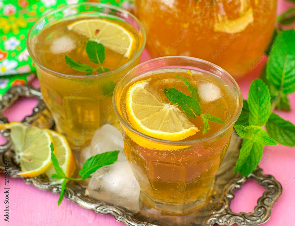 Sweet iced tea with mint, lemon and ice cubes Sweet iced tea with mint, lemon and ice cubes