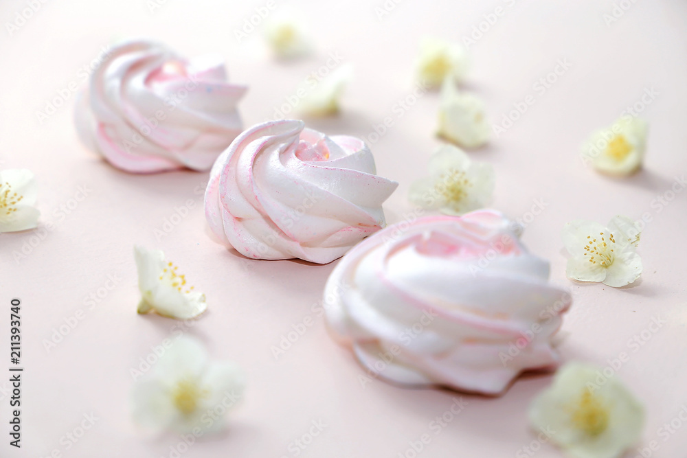 White homemade meringue or marshmallow on pink background with small white flowers