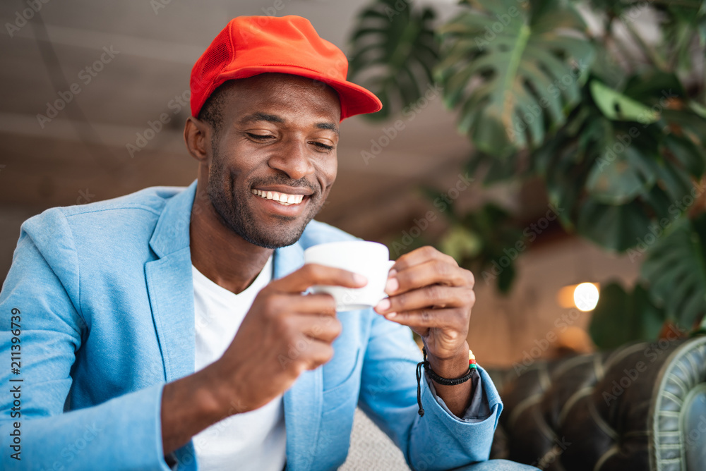 Portrait of beaming male looking at appetizing cup of coffee while holding it in arms Portrait of beaming male looking at appetizing cup of coffee while holding it in arms