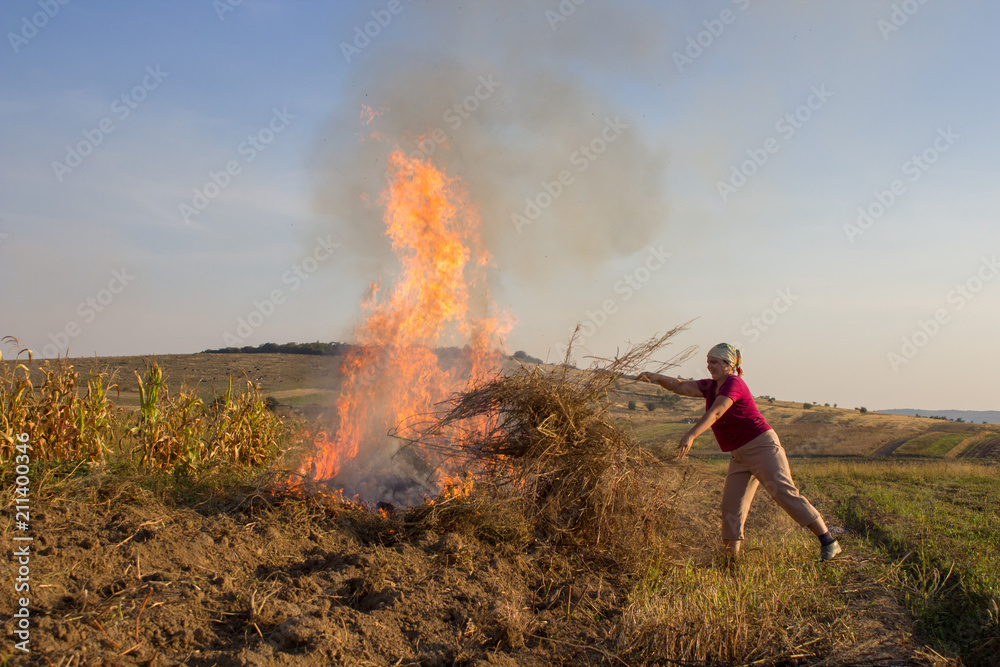 a woman throwing dry grass into the fire