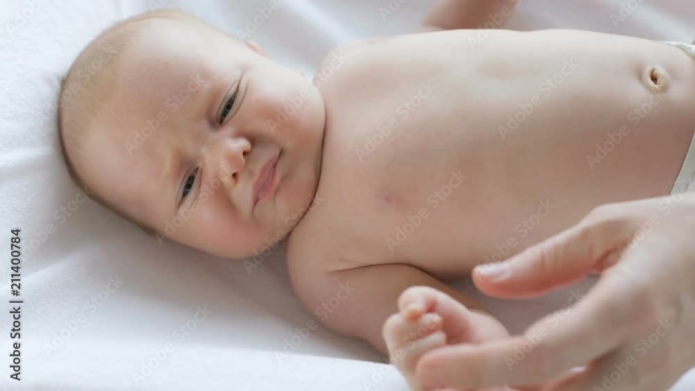 mom cares for a baby on the bed at the day time mom cares for a baby on the bed at the day time