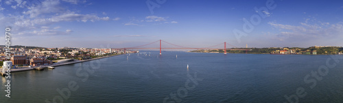 Aerial panoramic view of the city of Lisbon with sail boats on the Tagus River and the 25 of April Bridge (Ponte 25 de Abril) on the background; Concept for travel in Portugal and visit Lisbon