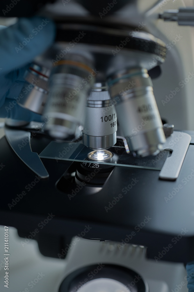 Fototapeta premium Scientist hands with microscope close-up shot in the laboratory