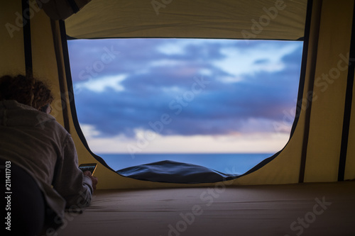 lonely independent strong middle age woman feeling the nature outdoor in a roof tent on the car. travel and lifestyle wanderlust concept for beautiful caucasian lady sitting in front of the ocean