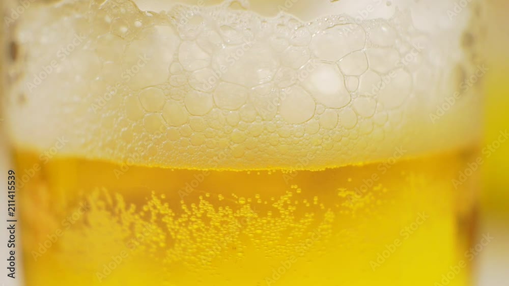 frothy light beer in a glass closeup. frothy light beer in a glass closeup.
