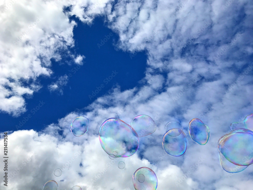 Soap bubbles against sky with clouds. Beautiful background image with big soap bubbles.

