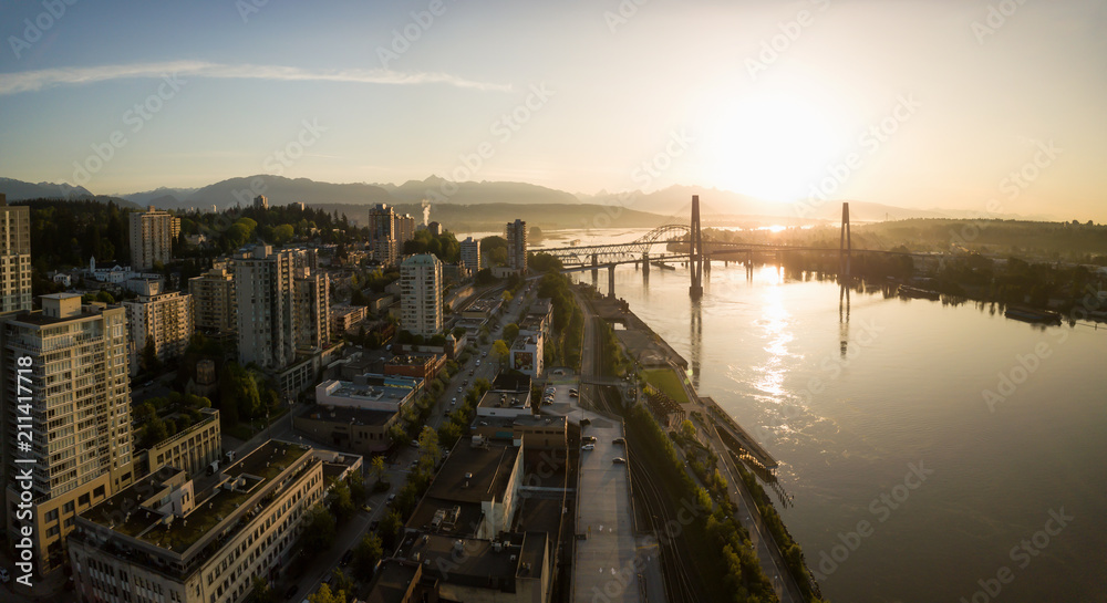 Aerial Panoramic view of Fraser River and Bridges during a vibrant sunrise. Taken in New Westminster, Greater Vancouver, British Columbia, Canada.