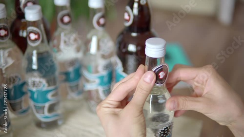 Close-up of a girl glues stickers on glass bottles with homemade alcohol