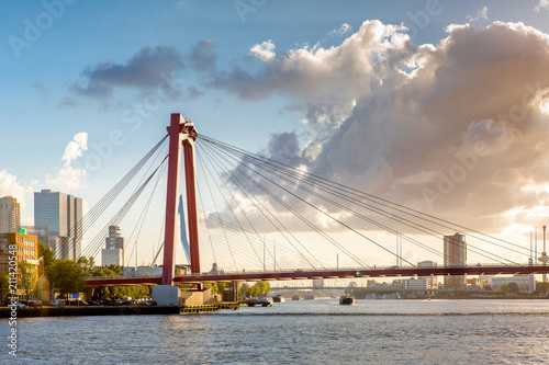 Sunset cityscape of Rotterdam with a highway bridge in the foreground  and downtown and the famous Erasmus bridge in the background against a blue sky