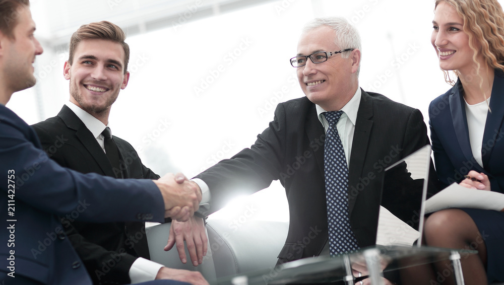 Partners concluding deal and shaking hands in the presence of team members Partners concluding deal and shaking hands in the presence of team members