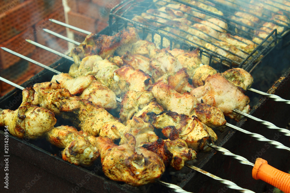 Preparation of a shish kebab from a chicken on a brazier on skewers. Close-up. Chicken shish kebab. Background.