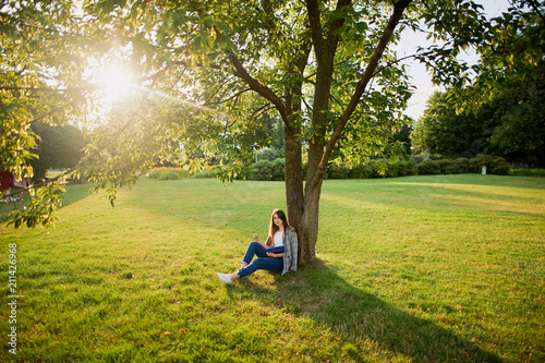 Pretty girl with her book in park background, sunset