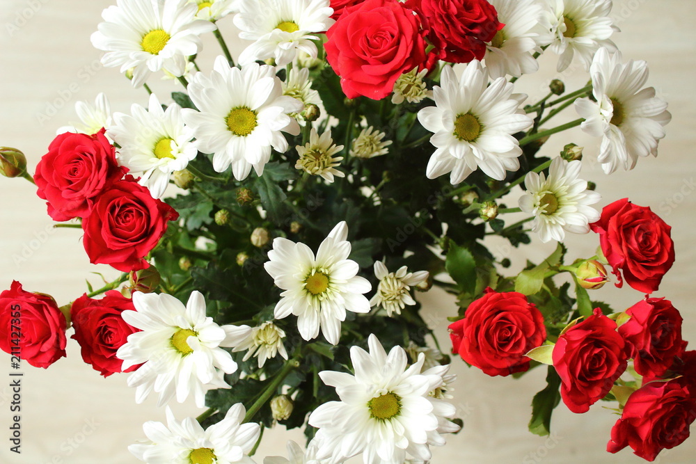 A bright beautiful bouquet of flowers from roses and chamomiles. Close-up. View from above. Background.