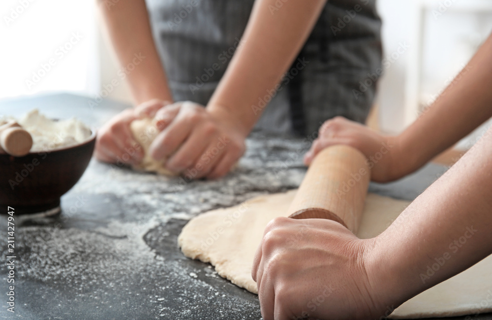 Woman rolling dough on table, closeup