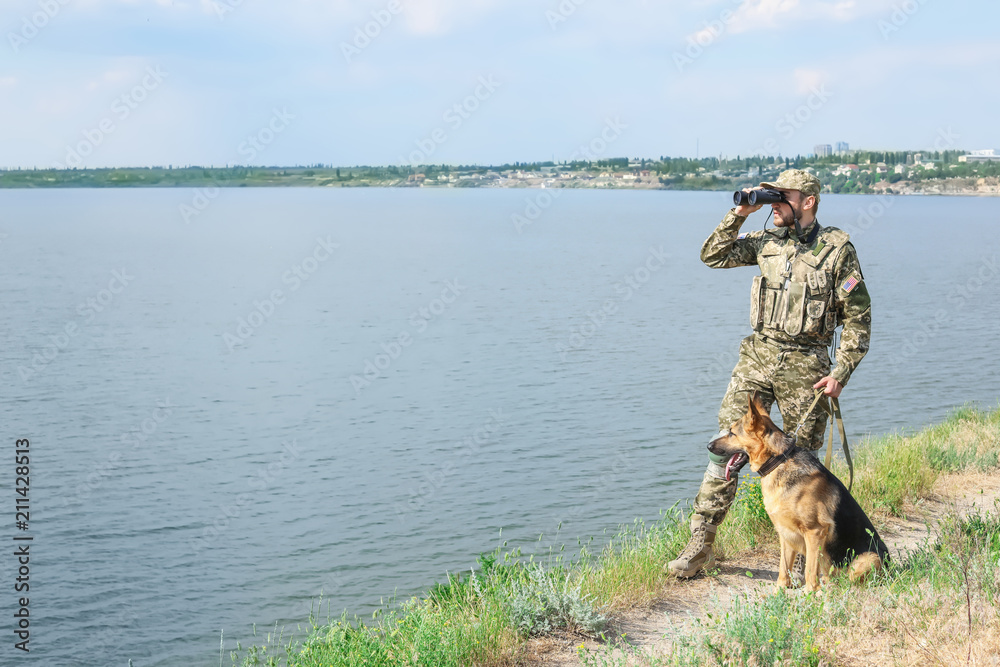 Naklejka premium Man in military uniform with German shepherd dog outdoors