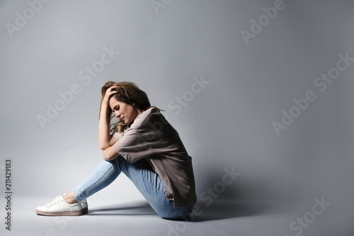 Foto Lonely depressed woman sitting on grey background