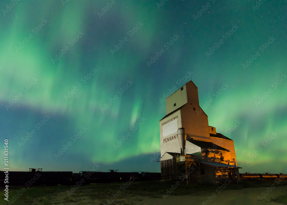 Fototapeta premium Aurora Borealis over a historic grain elevator in Pennant, Saskatchewan, Canada