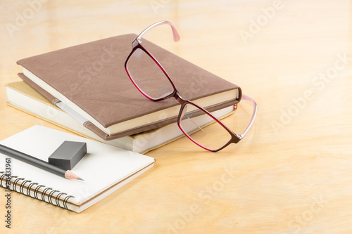 eyeglasses with books and stationary on wooden table, copy space for text. business and education concept.