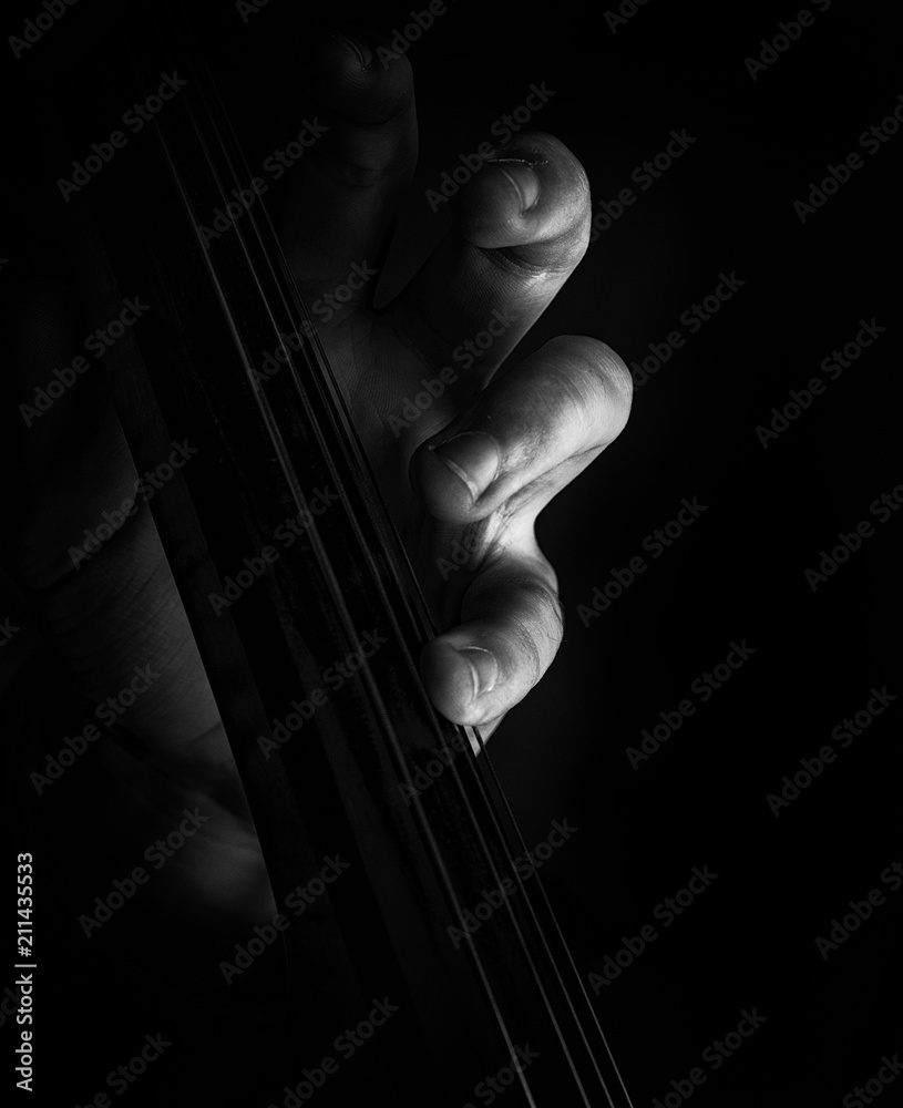 A classically trained musician plays cello, close up black and white