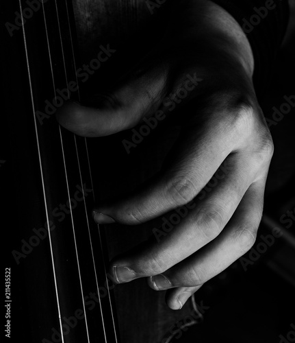 A classically trained musician plays cello, close up black and white