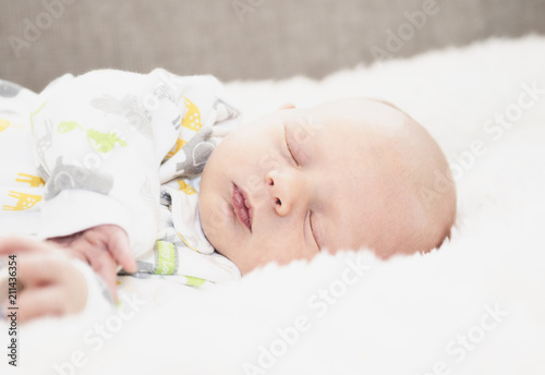 Sleeping Newborn in Comfortable Sleeper Pajamas on a White Soft Blanket