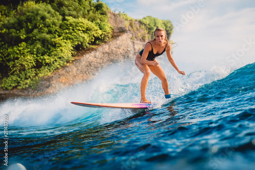 Surfer woman ride at surfboard on ocean wave. Woman in ocean during surfing.