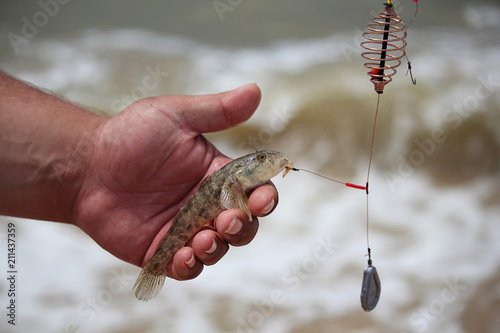 Fishing rod on the seashore, fishing in the sea. The fish is in the man's hand. Selective focus, side view, space for copy