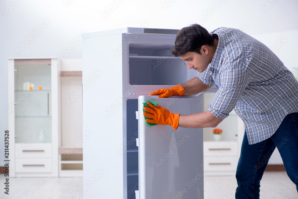 Man cleaning fridge in hygiene concept Man cleaning fridge in hygiene concept