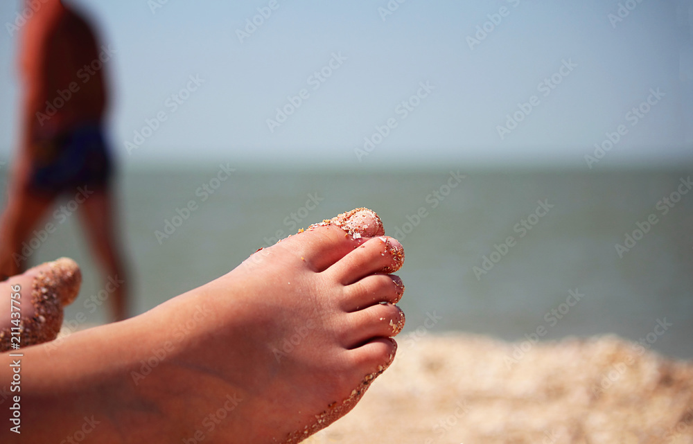 Marine background. The legs of a woman sunbathing against the background of the sea. Abstract background. Selective focus. Close-up, side view, copy space. Marine background. The legs of a woman sunbathing against the background of the sea. Abstract background. Selective focus. Close-up, side view, copy space.