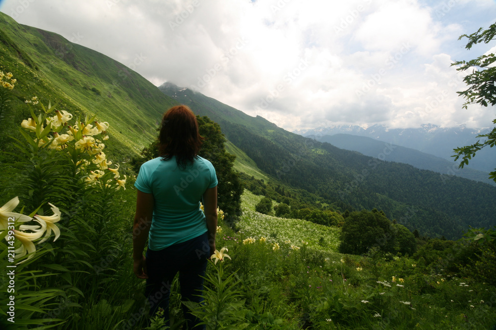 Young woman among the flowering meadows in the Caucasus mountains